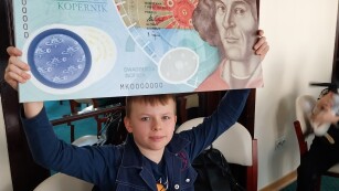 chłopiec trzyma w rękach duży banknot